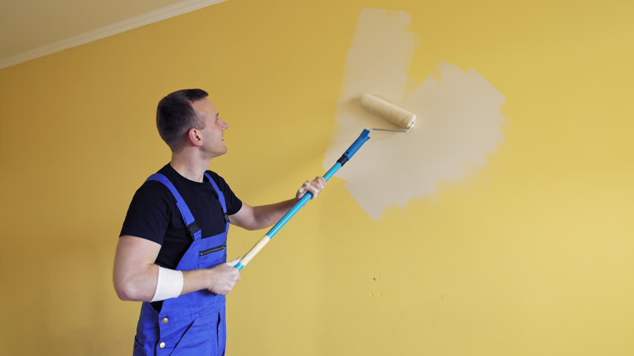 Handsome male painter doing room improvement. Attractive man improve house interior.