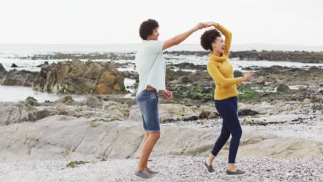 pareja afroamericana bailando juntos en las rocas cerca del mar