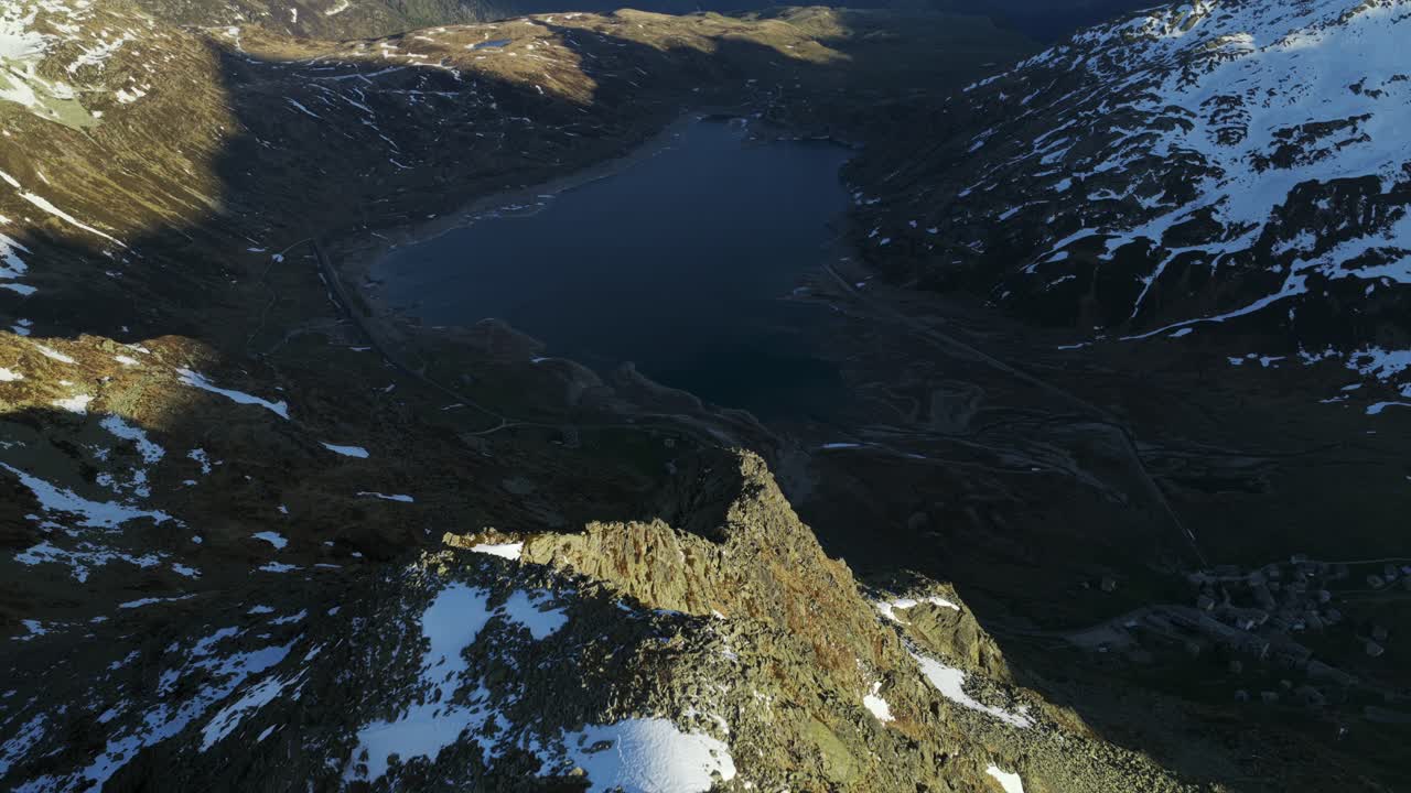 Breathtaking aerial view of the pristine Montespluga lake nestled amidst the snow capped Swiss Alps, showcasing the rugged beauty of the mountain landscape