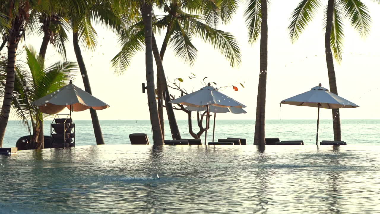 View of an empty quiet tropical beach with a swimming pool with no people, no tourists in the resort during evening