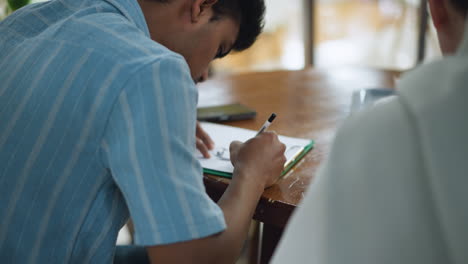 camera capturing shoulder and hand motion across paper while gripping pen, highlighting smooth drawing movement under soft light with shallow focus on artistic sketch process and body gesture
