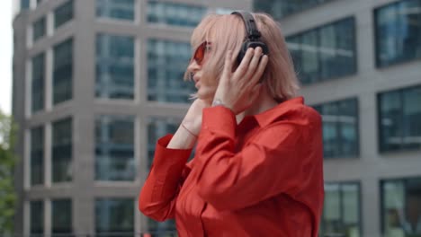 woman with pink hair listening to music in the city