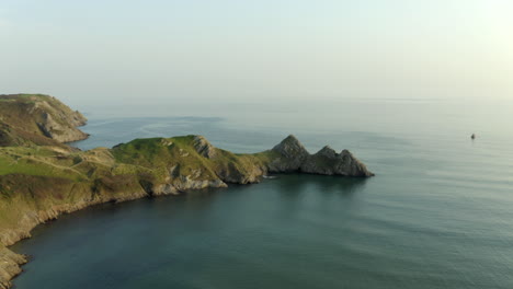 bellas imágenes de drones de la bahía de tres acantilados con mar en calma al atardecer en la península de gower, gales del sur