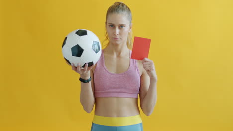 woman holding soccer ball and red card