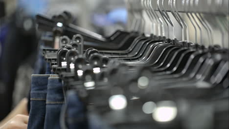woman in the store choosing jeans hanging on racks