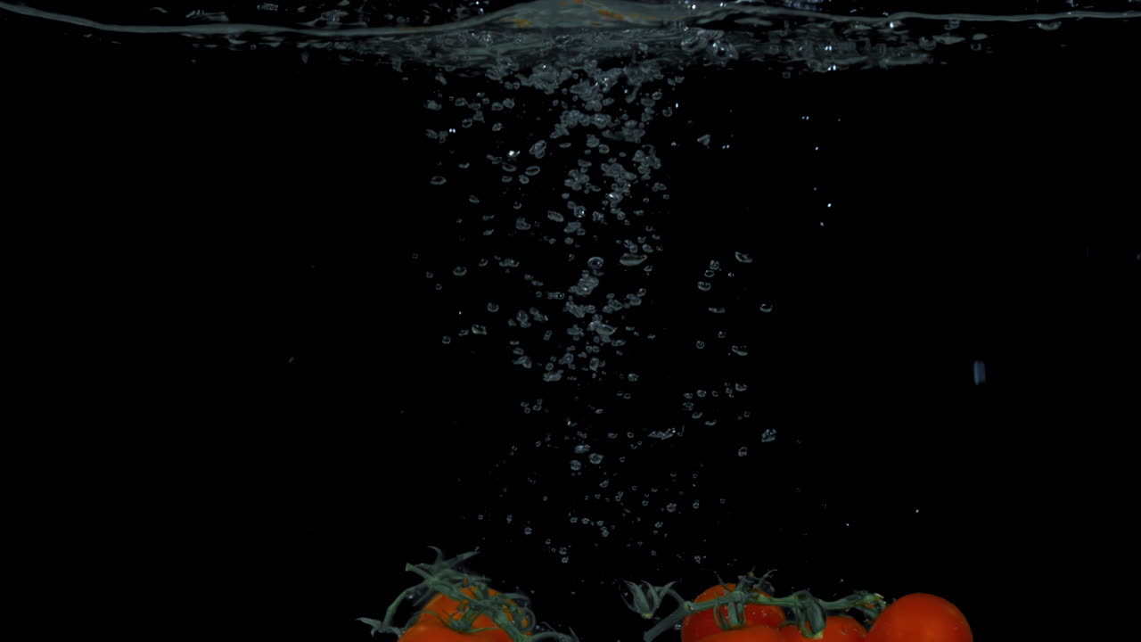 tomates salpicando bajo el agua.