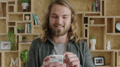 close up of attractive cheerful young man enjoying texting browsing using smartphone feeling connected