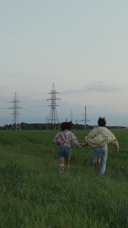 couple running in a field at sunset