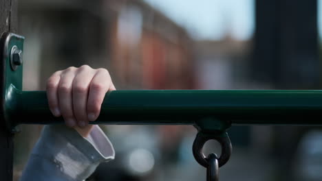 Slow-motion-close-up-of-a-child-reaching-her-hands-up-to-grab-part-of-a-playground-structure