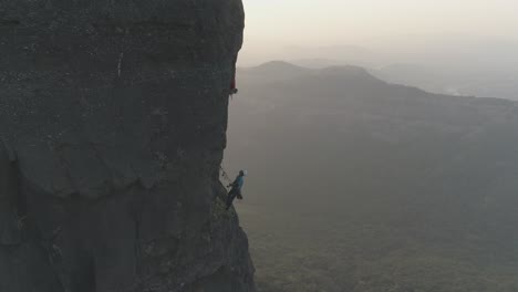 cinematic drone shot of rock climbers climbing a multi pitch sports route on a basalt rock pinnacle in the mountains of sahyadri range in india