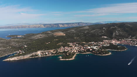 Drone-turning-right-to-reveal-the-beautiful-city-of-Hvar-with-a-boat-in-foreground