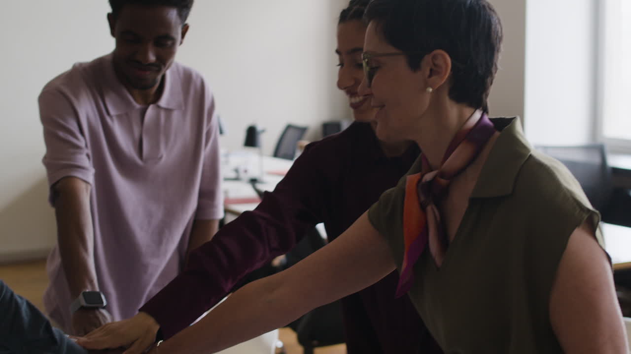 Diverse professionals demonstrate teamwork with a hand stack in an office