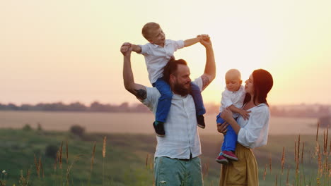 Glückliche-Kinder-Und-Ihre-Eltern-Freuen-Sich-Gemeinsam-Mit-Der-Sonne-Lebende-Natur-Und-Sonnenuntergang-An-Der-Frischen-Luft