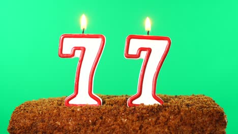 cake with the number 77 lighted candle. chroma key. green screen. isolated