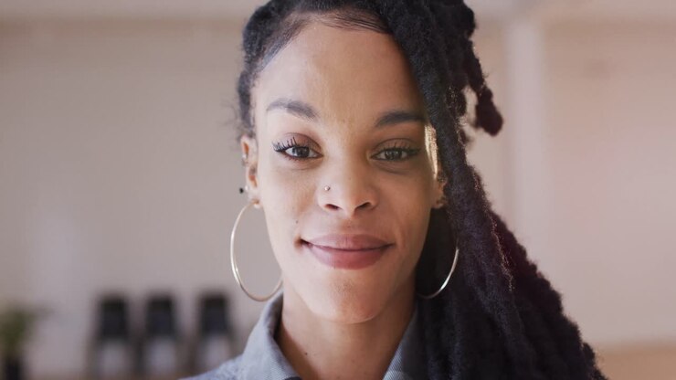 Portrait of happy biracial woman looking at camera in dance studio, slow motion