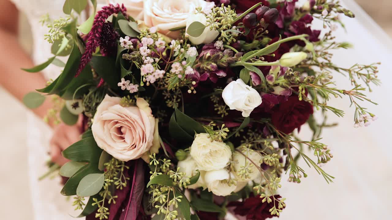 핑크 장미와 녹지 1080p 60fps로 야외에서 큰 웨딩 부케를 들고 있는 웨딩드레스를 입은 신부를 닫습니다