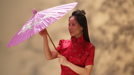 retrato de una joven asiática alegre con ropa tradicional roja abriendo una sombrilla sonriendo a la cámara