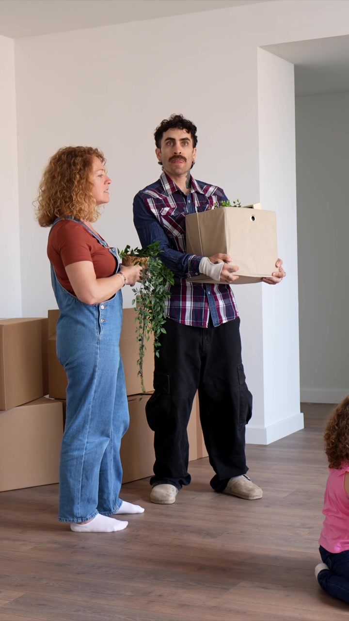 Young Couple Standing in New Home Surrounded by Moving Boxes