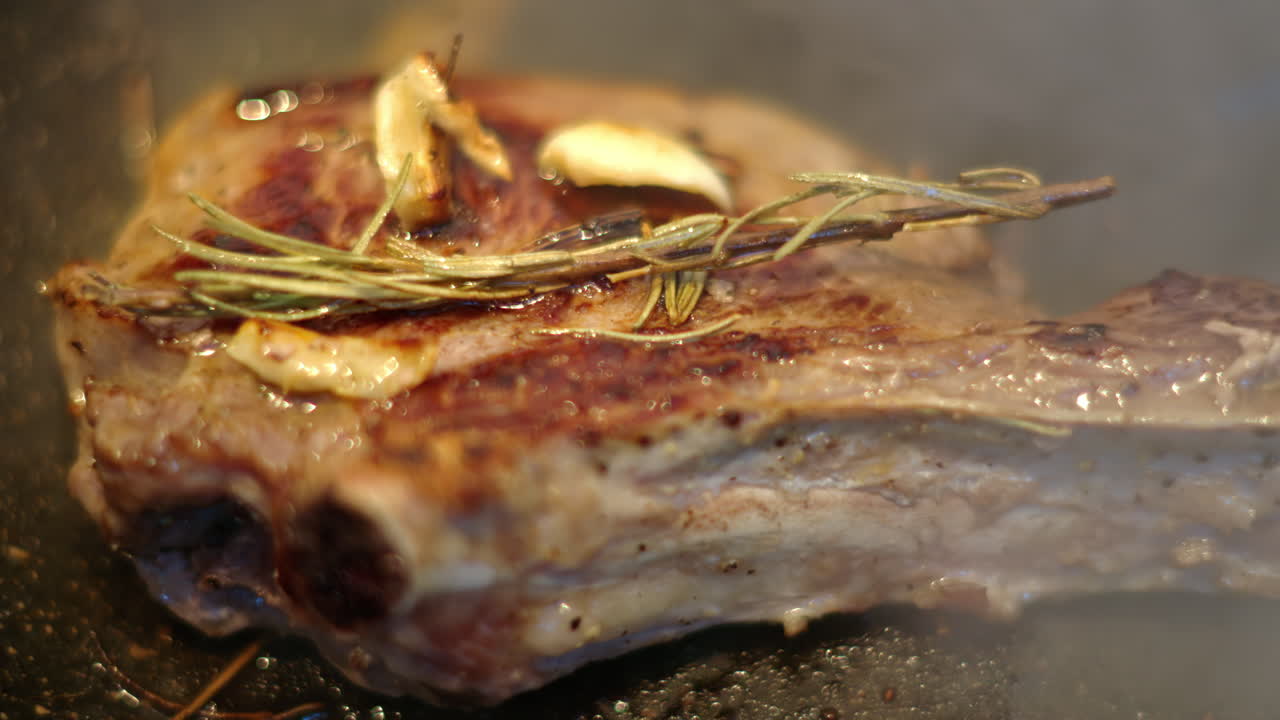 Cooked juicy steak meat beef being prepared with rosemary and garlic