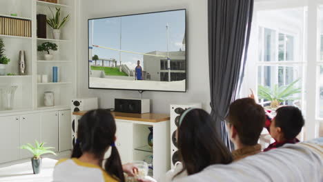 행복 한 가족 이 집 에서 함께 앉아서 tv 에서 육상 하이 점프 대회 를 시청 하고 있다