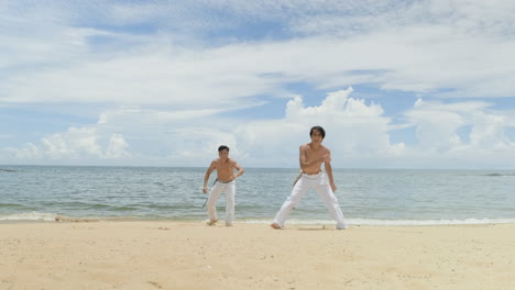 two men dancing capoeira on the beach