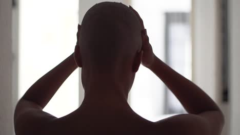 black woman touching head at home