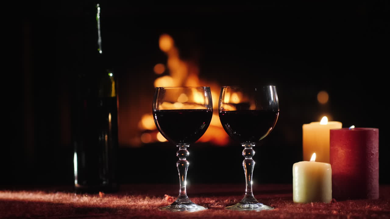 dos vasos con vino tinto contra el fondo de la chimenea donde arde el fuego