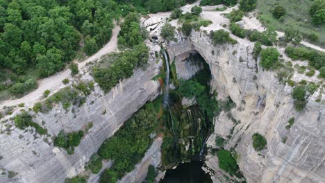 aerial view above rocky cliff edge waterfall cascading into water below