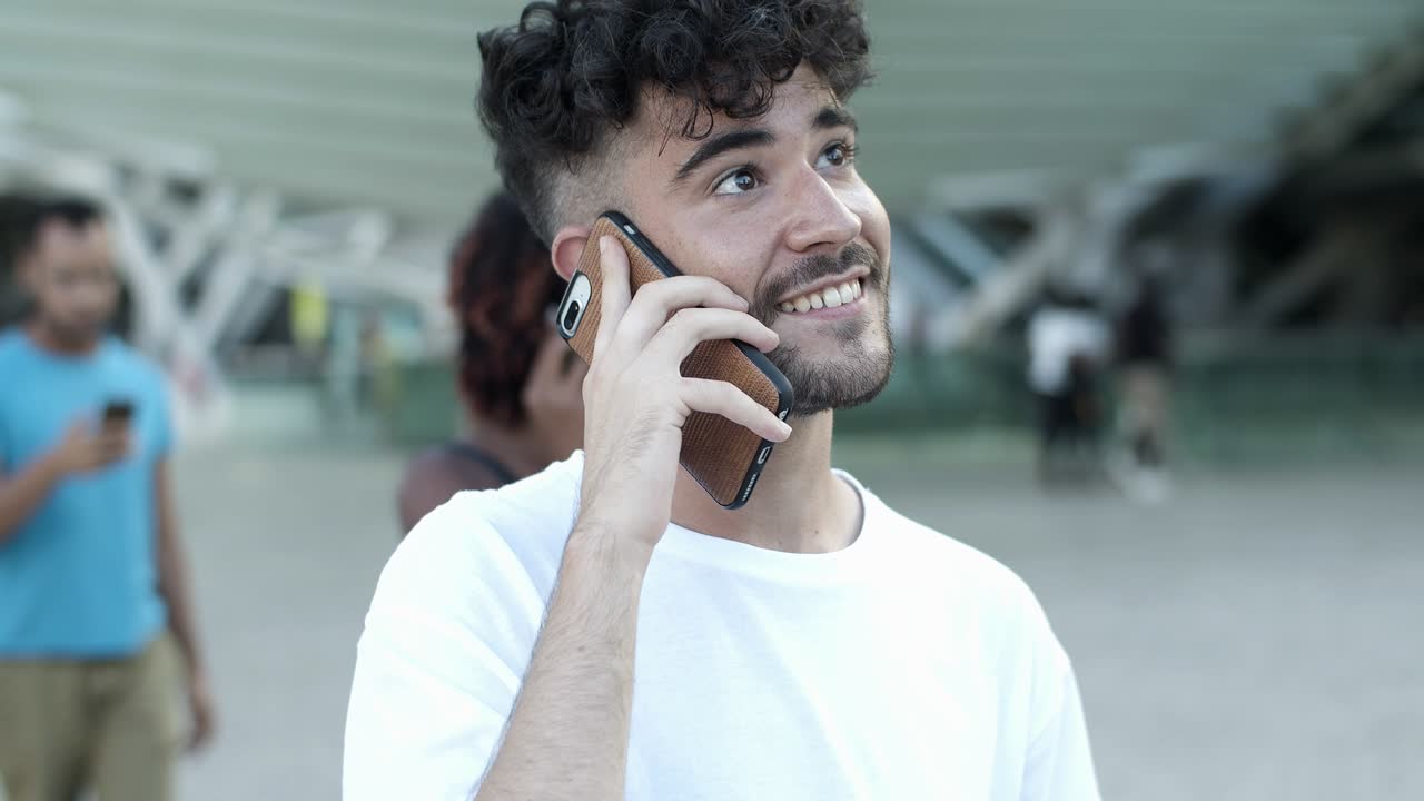 un joven sonriente hablando en un teléfono inteligente