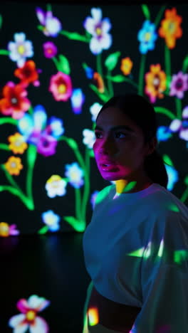 woman amidst vibrant floral light projections
