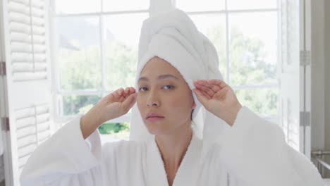 happy asian woman wearing towel on head in bathroom, in slow motion