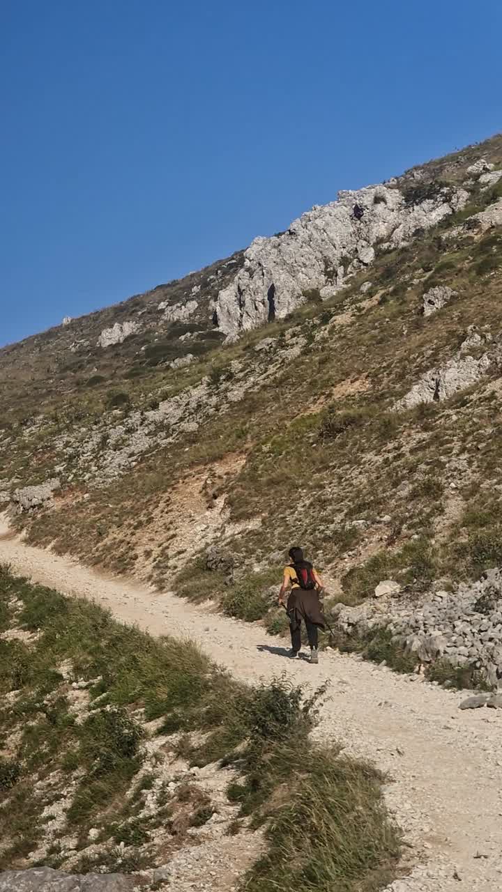 chica morena con bastones de caminar caminando en la ruta de los cuidados, entre poncebos y caín