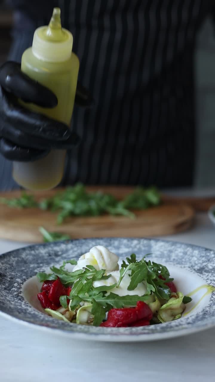 chef preparando una burrata y una ensalada de pimienta roja asada