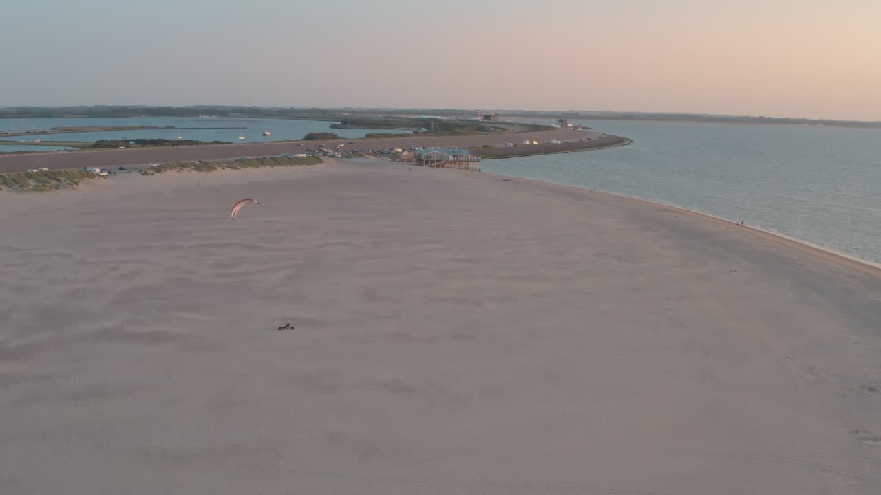drone cinemático - toma aérea de la playa de arena natural al atardecer con buggykiting en zelanda en el mar del norte, países bajos, 25p