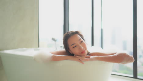 아름다운 젊은 여성이 거품 목욕을 하면서 완전히 이완됩니다