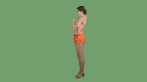 vista lateral de una joven encantadora que agita su mano con coqueteo y hace gestos para que vengas aquí. chica en un vestido naranja con franjas en una pantalla verde en el estudio. cámara lenta