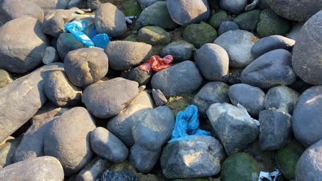 rocky river bank covered in trash, a stark reminder of an environmental issue