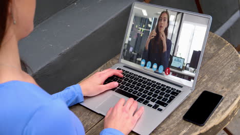 sección media de una mujer caucásica haciendo una videollamada con una colega en una computadora portátil
