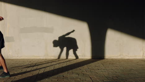 hombre bailando joven bailarín de calle breakdancing realizando varios movimientos de baile de estilo libre adecuado hombre de raza mixta practicando en la ciudad al atardecer con sombra en la pared