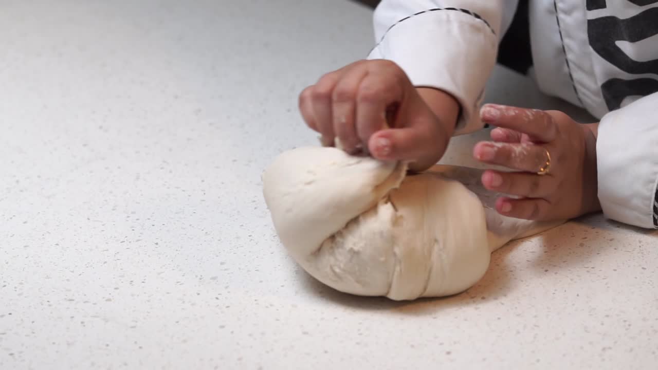 kneading white dough with hands on white table slow motion ready wide 