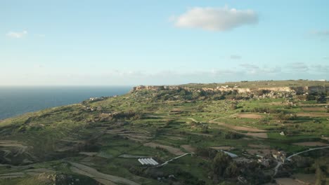 aerial: green high rugged cliffs overseeing mediterranean sea washing coastline in malta