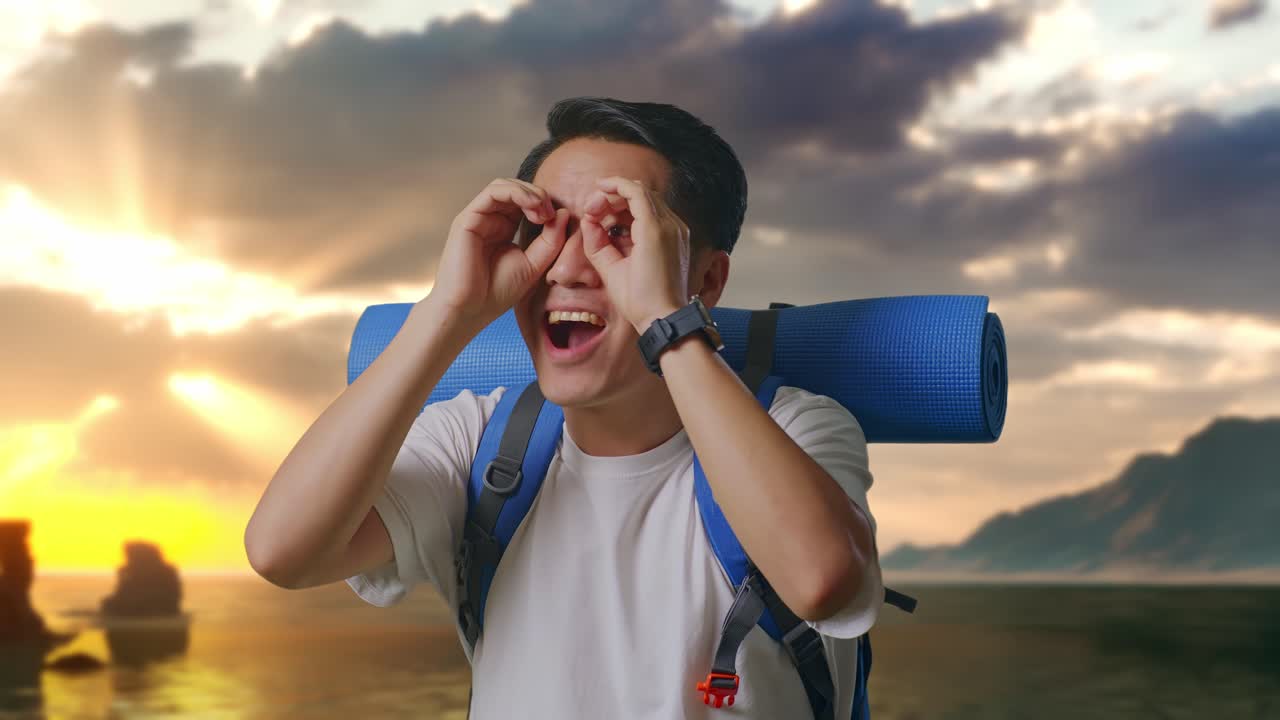 Close Up Of Asian Male Hiker With Mountaineering Backpack Making Binoculars Gesture Looking At Something Then Saying Wow on Beach
