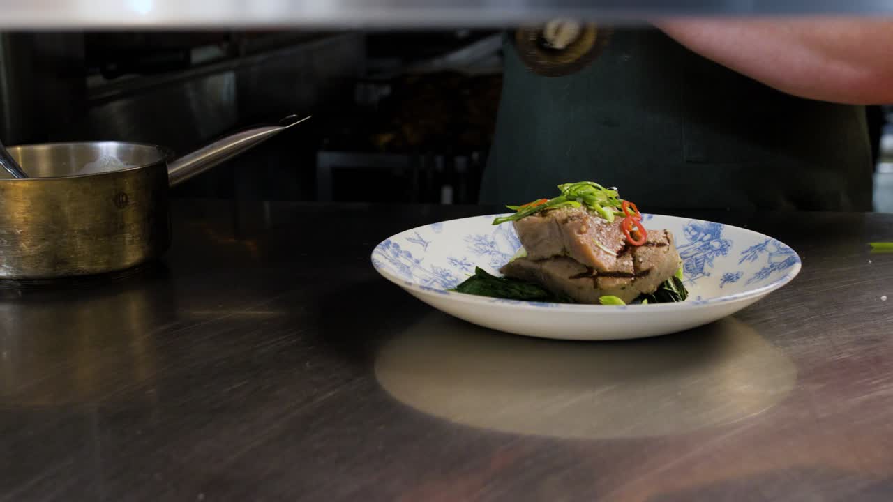 el chef agrega pimienta y sal al atún emplatado