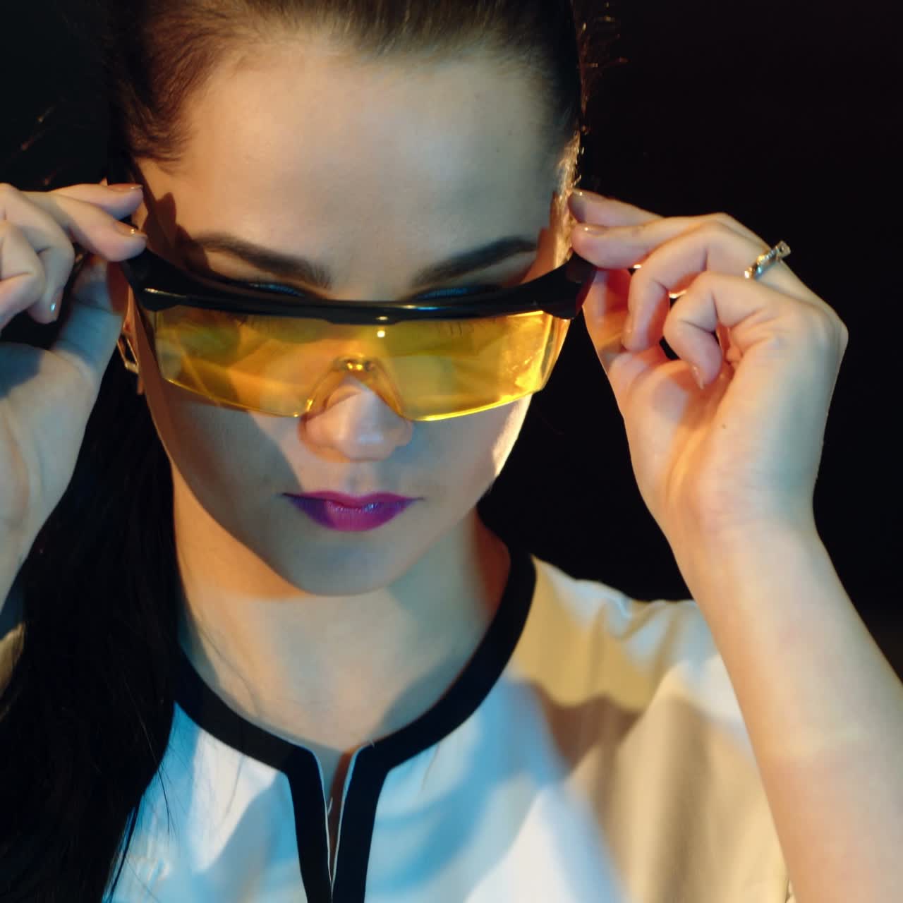 beautiful nurse with a hairdo is putting on eyeglasses with yellow glass and smiling in the laboratory