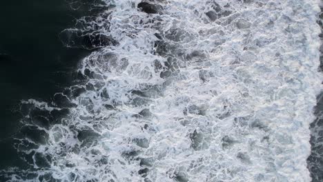 Top-down-aerial-view-of-giant-ocean-waves-crashing-and-foaming
