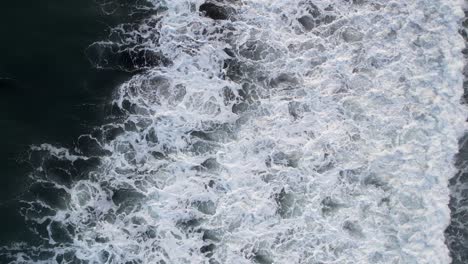 top down aerial view of giant ocean waves crashing and foaming