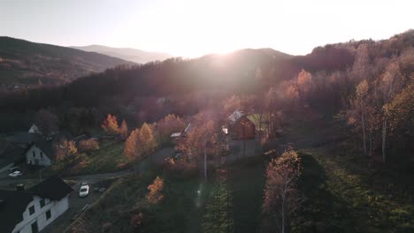 Vista-Aérea-De-Cabañas-De-Madera-En-Un-Bosque-Colorido-Al-Atardecer