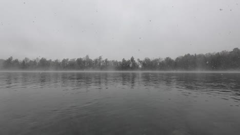 Es-Schneit-Auf-Einem-Mystischen-See-Mit-Türkisfarbenem-Wasser-An-Einem-Bewölkten,-Nebligen-Tag