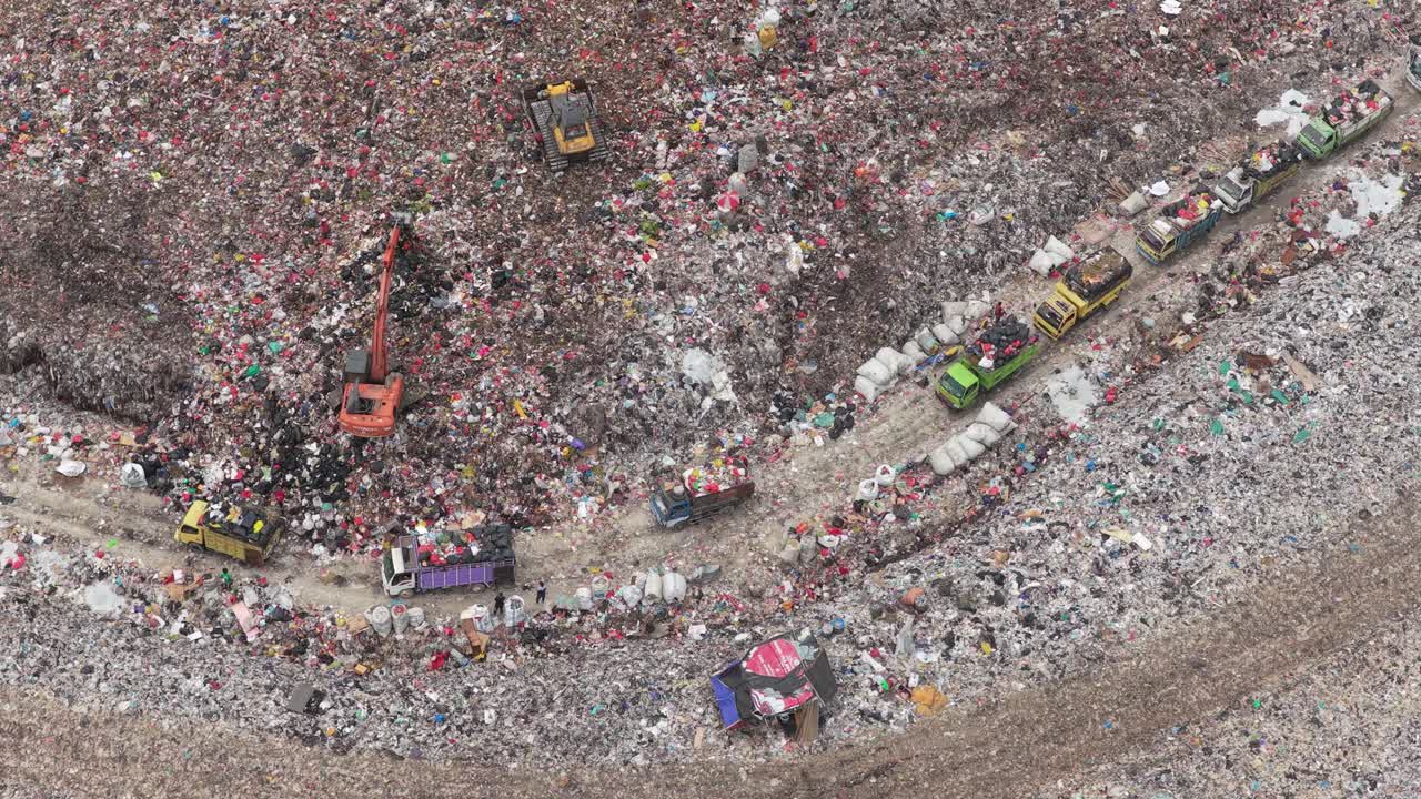 Vista aerea di un'enorme discarica con camion ed escavatori che spostano i rifiuti