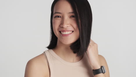 asian woman preening her hair on camera.